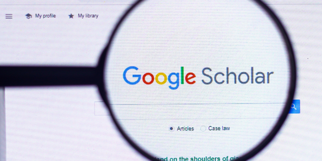 In this photo illustration, the homepage of the Google Scholar website seen on a computer screen through a magnifying glass.