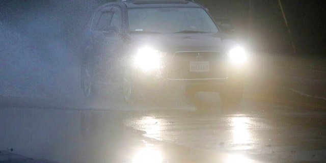 An automobile drives through a flooded portion of Mountain Boulevard on Tuesday, Dec. 27, 2022, in Oakland, California.