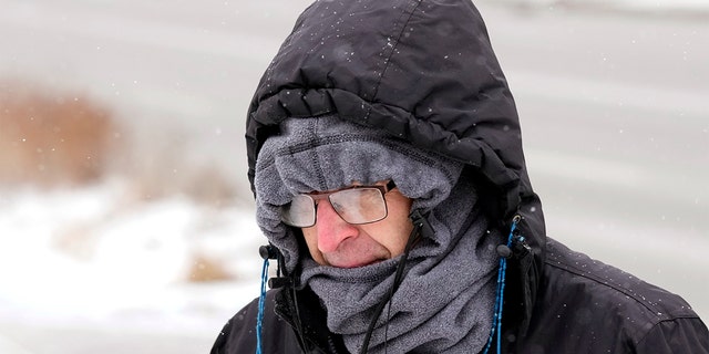 On Wednesday, December 21, 2022, Greg Behrens of Des Moines, Iowa, tries to stay warm while walking down a snow-covered sidewalk.
