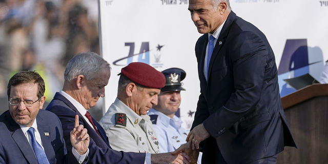 Israeli Prime Minister Yair Lapid, right, shake hands with Israel's Defense Minister Benny Gantz during a graduation ceremony for new Israel's air force pilots in Hatzerim base near the southern Israeli city of Beersheba, on Wednesday, Dec. 28.