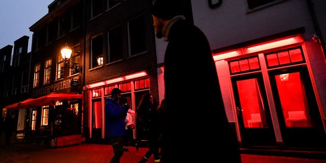 People walk near a red traffic light in the red light district of Amsterdam, Netherlands, on December 10, 2022.