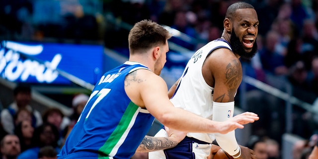 Los Angeles Lakers forward LeBron James instructs his teammates on the floor as Dallas Mavericks guard Luka Doncic defends him in the first half of an NBA basketball game in Dallas, Sunday, Dec. 25, 2022. 