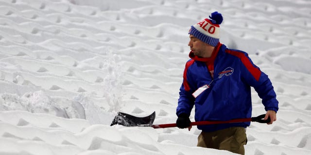 Stadium workers clear snow off the field prior to a game between the Miami Dolphins and Buffalo Bills at Highmark Stadium Dec. 17, 2022, in Orchard Park, N.Y.