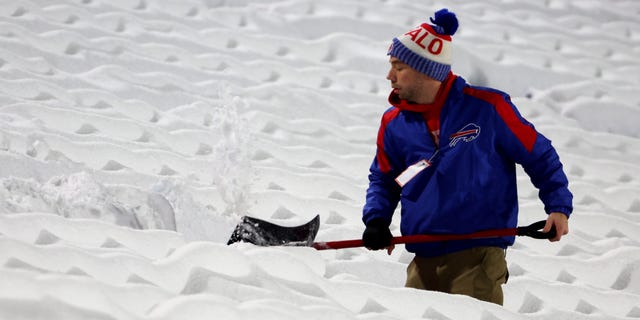 Stadium workers clear snow off the field prior to a game between the Miami Dolphins and Buffalo Bills at Highmark Stadium Dec. 17, 2022, in Orchard Park, N.Y.