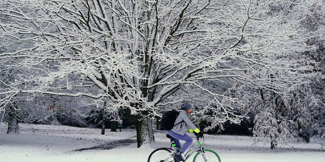 A person cycles through the snow in Greenwich Park, London, Monday, Dec. 12, 2022. Snow and ice have swept across parts of the UK, with cold wintry conditions set to continue for days. 