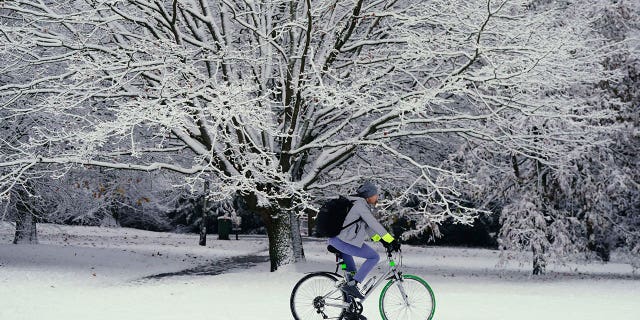 A person cycles through the snow in Greenwich Park, London, Monday, Dec. 12, 2022. Snow and ice have swept across parts of the UK, with cold wintry conditions set to continue for days. 