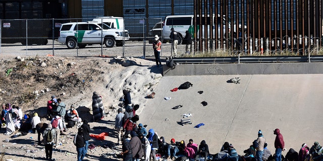 FILE - Migrants wait to cross the U.S.-Mexico border from Ciudad Juárez, Mexico, next to U.S. Border Patrol vehicles in El Paso, Texas, Wednesday, Dec. 14, 2022.