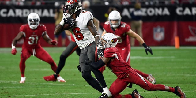 Julio Jones #6 of the Tampa Bay Buccaneers is tackled by Budda Baker #3 of the Arizona Cardinals after making a catch in overtime during the game at State Farm Stadium on December 25, 2022 in Glendale, Arizona.