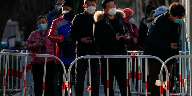 Residents wait in line for their routine COVID-19 test at a coronavirus testing site in Beijing, Dec. 7, 2022.