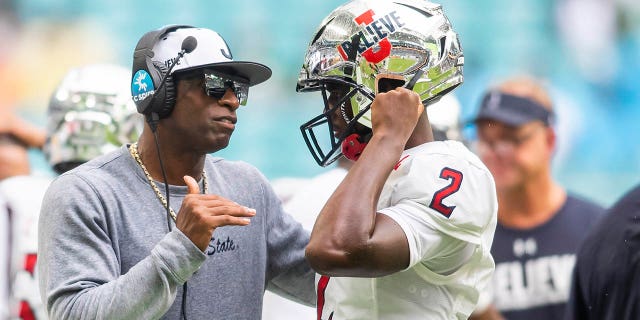 El entrenador en jefe de los Jackson State Tigers, Deion Sanders, habla con el mariscal de campo Shedeur Sanders durante el Orange Blossom Classic contra los Florida A&M Rattlers el 5 de septiembre de 2021 en el Hard Rock Stadium en Miami Gardens.