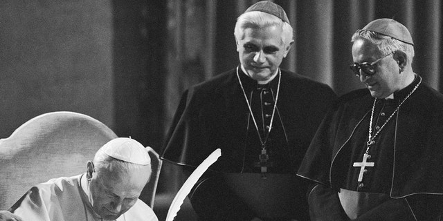 Pope John Paul II, seated, signs the new Roman Catholic code of canon law during a ceremony at the Vatican with former West German Cardinal Joseph Ratzinger, center, and Venezuelan Archbishop Rosalio Jose Castillo Lara.