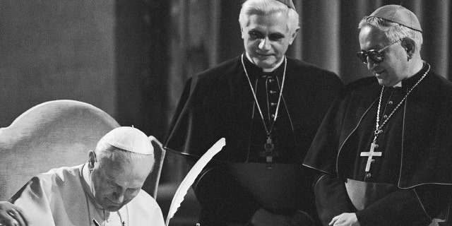 Pope John Paul II, seated, signs the new Roman Catholic code of canon law during a ceremony at the Vatican with former West German Cardinal Joseph Ratzinger, center, and Venezuelan Archbishop Rosalio Jose Castillo Lara.