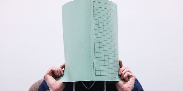 The defendant in the Wermelskirchen abuse complex holds a folder in front of his face in a courtroom in Cologne, Germany, on Dec. 6, 2022. 