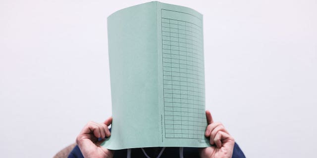 The defendant in the Wermelskirchen abuse complex holds a folder in front of his face in a courtroom in Cologne, Germany, on Dec. 6, 2022. 