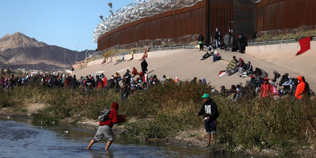 Migrants walk across the Rio Grande to surrender to U.S. Border Patrol agents in El Paso, Texas, Dec. 13, 2022.