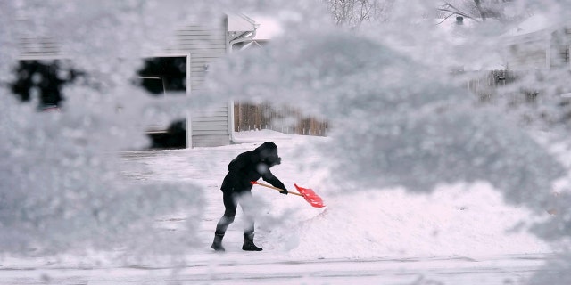 A local resident shovels snow off the end of a driveway, Thursday, Dec. 22, 2022, in Urbandale, Iowa. (AP Photo/Charlie Neibergall)