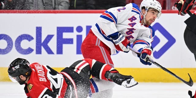 Filip Chytil #72 of the New York Rangers completes a shot on goal after colliding with Colin Blackwell #43 of the Chicago Blackhawks in the first period on December 18, 2022, at United Center in Chicago, Illinois.