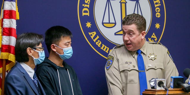 Carl Chan, left, and Jihao Wu, father of victim Jasper Wu, listen to California Highway Patrol Assistant Chief Jason Reardon announce multiple arrests in the fatal shooting of toddler Jasper Wu in Oakland, California, on Dec. 15, 2022.