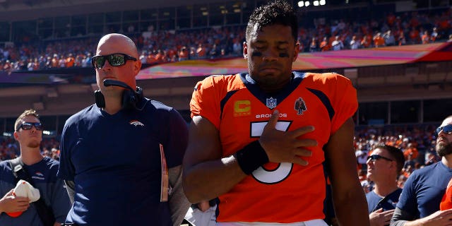 Denver Broncos head coach Nathaniel Hackett, left, and Russell Wilson (3) take a moment during the national anthem before playing the Houston Texans at Empower Field At Mile High on September 18, 2022 in Denver, Colorado. 