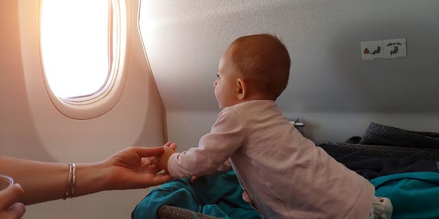 Bebé se sienta en el moisés de un avión de primera clase