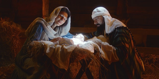 Gender-neutral 'controversial' production of 'Jesus Christ Superstar' features non-binary Jesus 2 Mother Mary and Saint Joseph caressing baby Jesus sleeping in the manger under bright divine light after birth in a stable in Bethlehem.