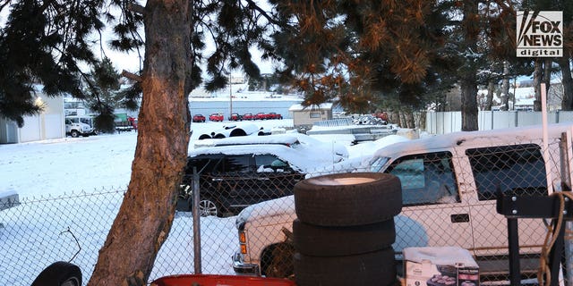 Vehicles towed from the Idaho quadruple homicide crime scene are stored in an outdoor car lot. Photo shows one of the vehicles, a dark-colored SUV, covered in snow and near a fence.