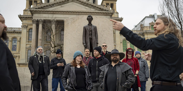 Minister Adam gathers with other members of the Satanic Temple of Illinois in front of the Abraham Lincoln statue on Dec. 6, 2022, outside the Illinois State Capitol in Springfield before installing their seasonal display alongside a Christmas tree and menorah inside the rotunda. (Brian Cassella/Chicago Tribune/Tribune News Service via Getty Images) 