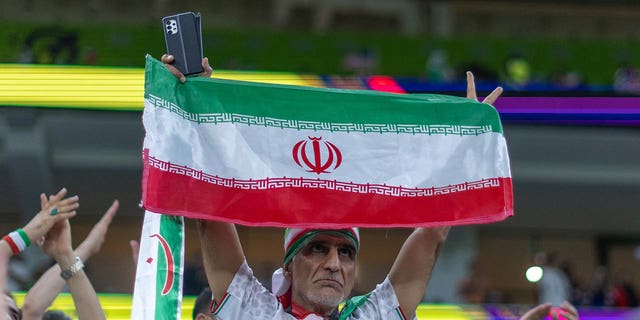 A fan holds the Iranian flag during the World Cup match between Iran and U.S. in Doha, Qatar, on Nov. 30, 2022.