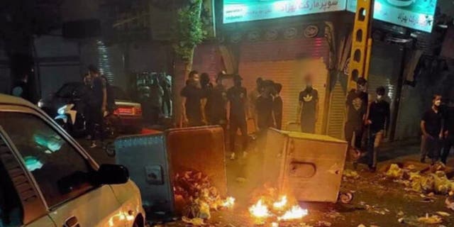 Protesters gather around burning rubble in the streets of Iran.