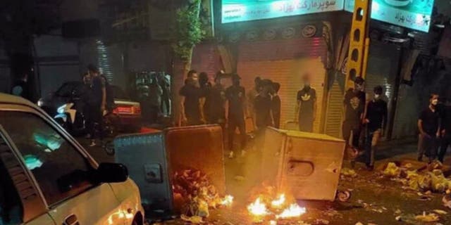 Protesters gather around burning rubble in the streets of Iran. 