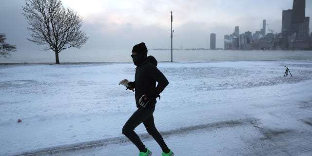 A jogger runs along Lake Michigan at sunrise as temperatures hover about -8 degrees on December 22, 2022, in Chicago, Illinois. (Photo by Scott Olson/Getty Images)