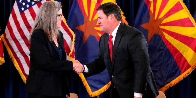 Katie Hobbs, the Democratic governor-elect and current secretary of state, left, shakes hands with Republican Gov.  Doug Ducey after she signed the official certification for the Arizona general election canvas during a ceremony at the Arizona Capitol in Phoenix, Dec. 5, 2022.