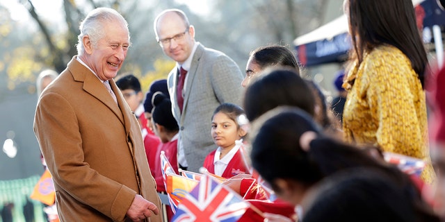 Britain's King Charles III smiles as he talks to flag-waving local school children during a visit to the newly built Guru Nanak Gurdwara, in Luton, England on Tuesday, December 6, 2022. 