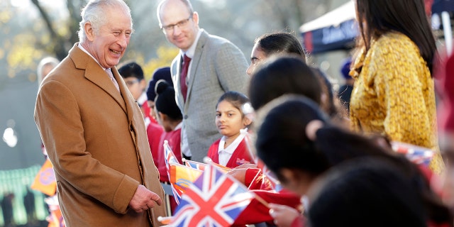 Britain's King Charles III smiles as he talks to flag-waving local school children during a visit to the newly built Guru Nanak Gurdwara, in Luton, England on Tuesday, December 6, 2022. 