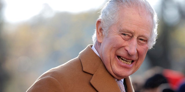 Britain's King Charles III smiles as he talks to flag-waving local school children during a visit to the newly built Guru Nanak Gurdwara, in Luton, England on Tuesday, December 6, 2022.