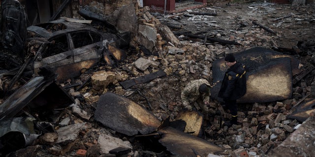 A Ukrainian firefighter and soldier inspect a destroyed house after a Russian drone attack in the village of Stary Bezradichy, Kyiv region, Ukraine, on Monday, December 19, 2022.