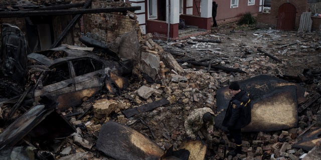 Um bombeiro e um soldado ucraniano inspecionam uma casa destruída após um ataque de drone russo na vila de Stary Bezradichy, região de Kyiv, Ucrânia, na segunda-feira, 19 de dezembro de 2022.