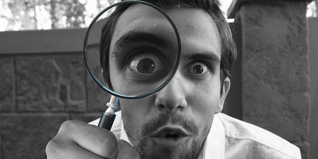 Man looking into magnifying glass
