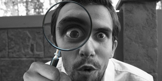 Man looking into magnifying glass