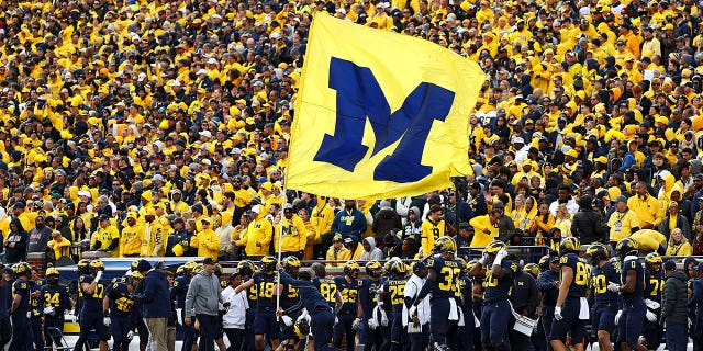 A cheerleader runs a Michigan Wolverines flag down the field after a touchdown during a game against the Penn State Nittany Lions at Michigan Stadium on October 15, 2022, in Ann Arbor, Michigan. 