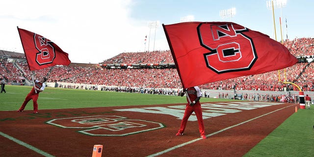North Carolina State Wolfpack cheerleaders wave flags after a touchdown against the Troy Trojans at Carter-Finley Stadium, Sept. 5, 2015, in Raleigh, NC