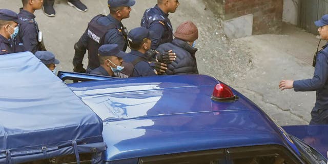 Nepalese police escort Charles Sobhraj, in brown cap, to the immigration office, in Kathmandu, Nepal, Friday, Dec. 23, 2022. 