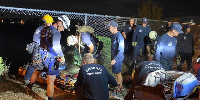 The Phoenix Fire Department cuts open a chain-link fence before rappelling down two 100-foot cliffs to rescue a suspect in a police pursuit.