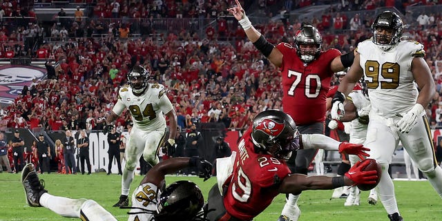 Rachaad White (29) of the Tampa Bay Buccaneers scores a touchdown against Demario Davis (56) of the New Orleans Saints late in the fourth quarter during a game at Raymond James Stadium Dec. 5, 2022, in Tampa, Fla. The Bucs defeated the Saints 17-16.