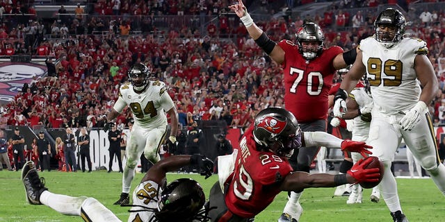 Rachaad White #29 of the Tampa Bay Buccaneers scores a touchdown against Demario Davis #56 of the New Orleans Saints late in the fourth quarter during the game at Raymond James Stadium on December 05, 2022 in Tampa, Florida. The Tampa Bay Buccaneers defeated the New Orleans Saints with a score of 17 to 16.