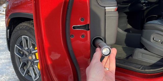 A rechargeable flashlight is stored in the door.
