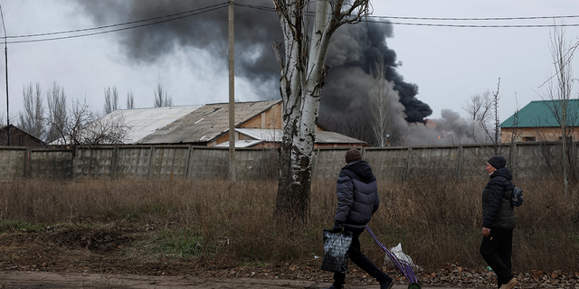 Two people walk past an industrial building that received a missile attack as Russia's assault on Ukraine continued amid intense shelling in Bakhmut, Ukraine December 25, 2022.