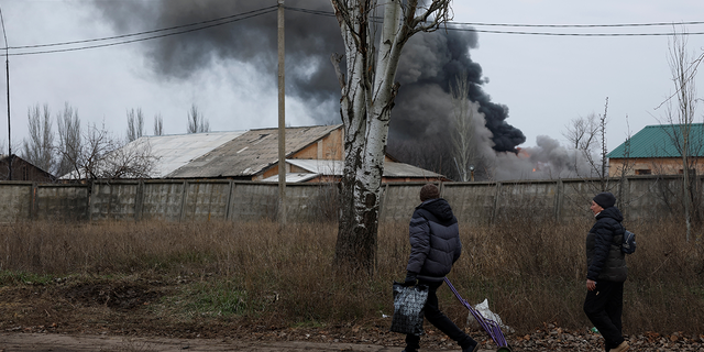 Two people walk past an industrial building that received a missile strike, as Russia's attack on Ukraine continues, during intense shelling on Christmas Day at the frontline in Bakhmut, Ukraine, December 25, 2022.