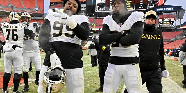 Shy Tuttle #99 and Paulson Adebo #29 of the New Orleans Saints pose for a photo after a win over the Cleveland Browns at FirstEnergy Stadium on December 24, 2022 in Cleveland, Ohio. 