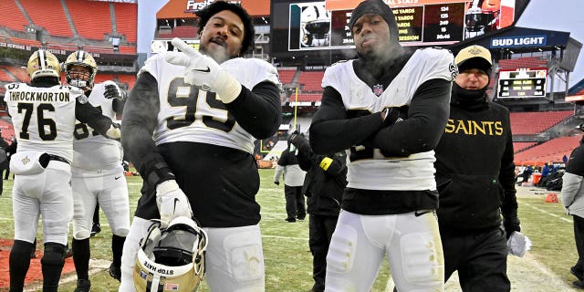 Shy Tuttle #99 and Paulson Adebo #29 of the New Orleans Saints pose for a photo after a win over the Cleveland Browns at FirstEnergy Stadium on December 24, 2022 in Cleveland, Ohio.